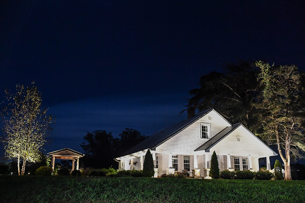 LED lighting illuminating a white home in the country