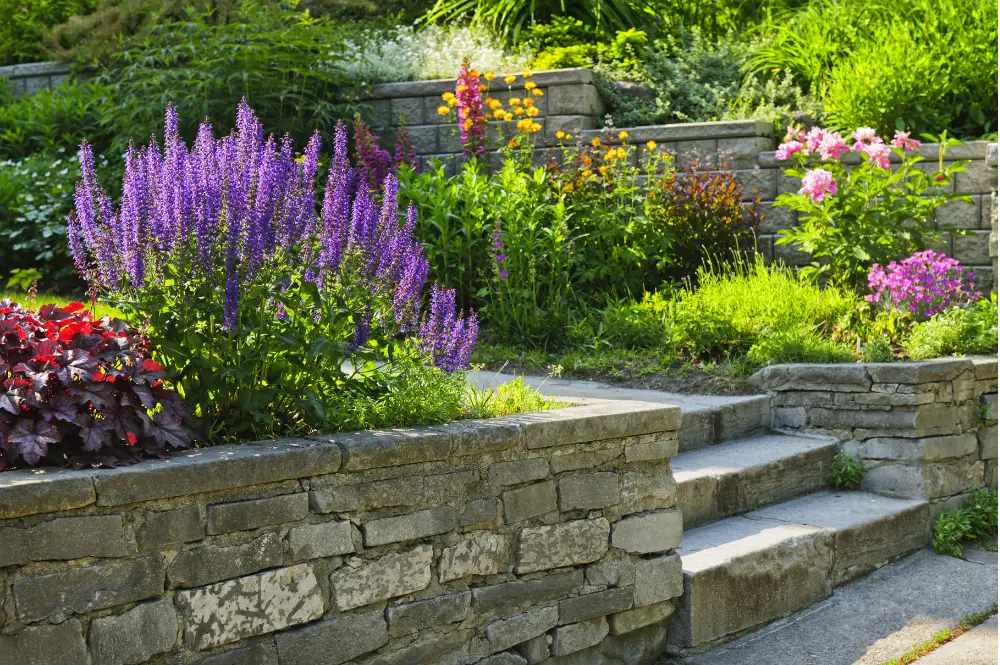 A stone wall adorned with vibrant flowers and lush plants, showcasing suitable landscaping ideas Charlotte, NC.